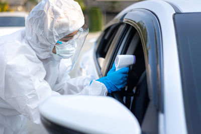 Medical staff with ppe use infrared thermometer gun to check body temperature at drive thru