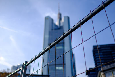 Low angle view of metal fence by buildings in city against sky