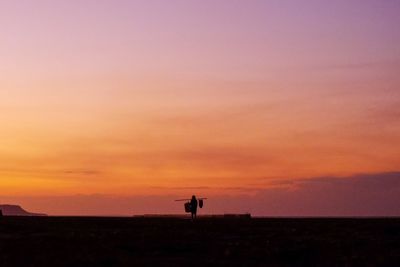 Silhouette people standing on field against sky during sunset