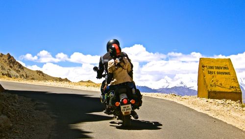 Rear view of man on road against sky on sunny day