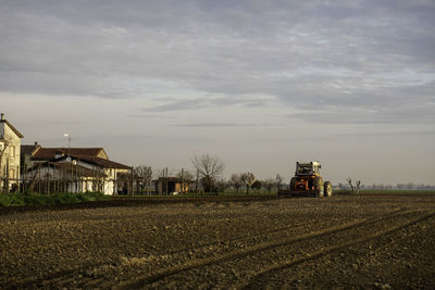 Houses by agricultural field against sky