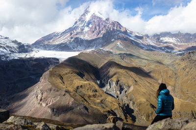 Rear view of woman on snowcapped mountains against sky