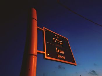 Low angle view of illuminated information sign against blue sky