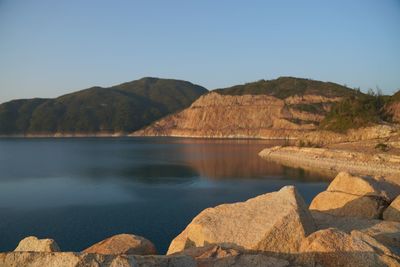 Scenic view of lake and mountains against clear blue sky