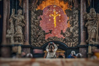 Rear view of woman photographing in church