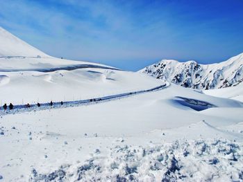 Snow covered landscape against blue sky