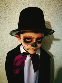 Portrait of boy wearing sunglasses against wall during halloween