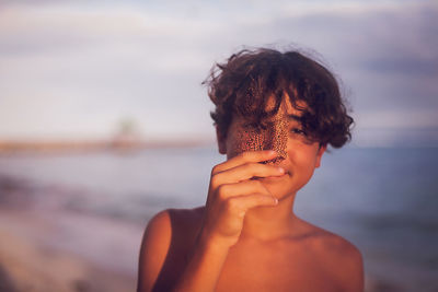 Portrait of shirtless man at beach against sky