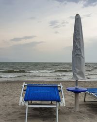 Deck chairs on beach against sky