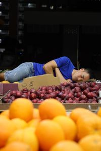 Man sleeping by fruits for sale at market stall