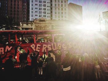 People on illuminated city against sky