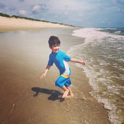 Full length of boy on beach against sky