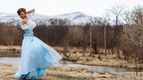 Woman in dress standing at lakeshore