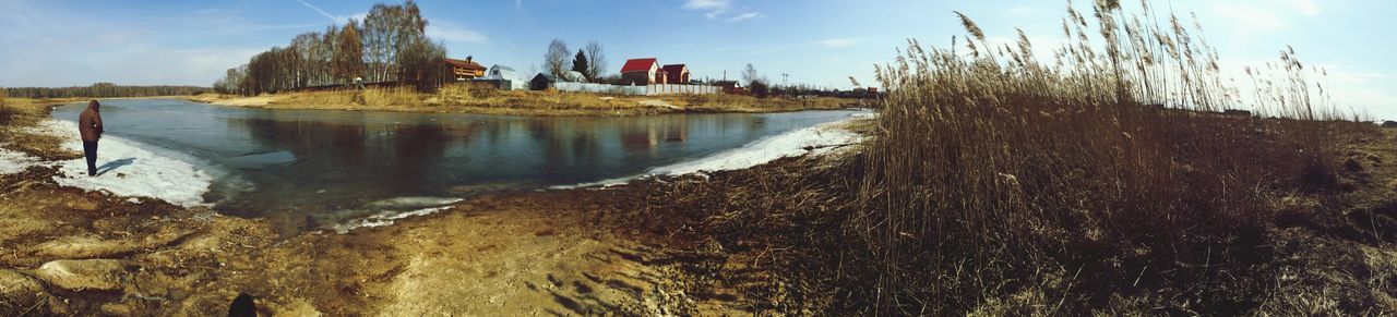 sky, water, building exterior, cloud - sky, cloud, built structure, tranquility, nature, sunlight, blue, tranquil scene, architecture, day, lake, reflection, scenics, grass, outdoors, sea, plant