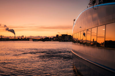 Scenic view of sea by buildings against sky during sunset