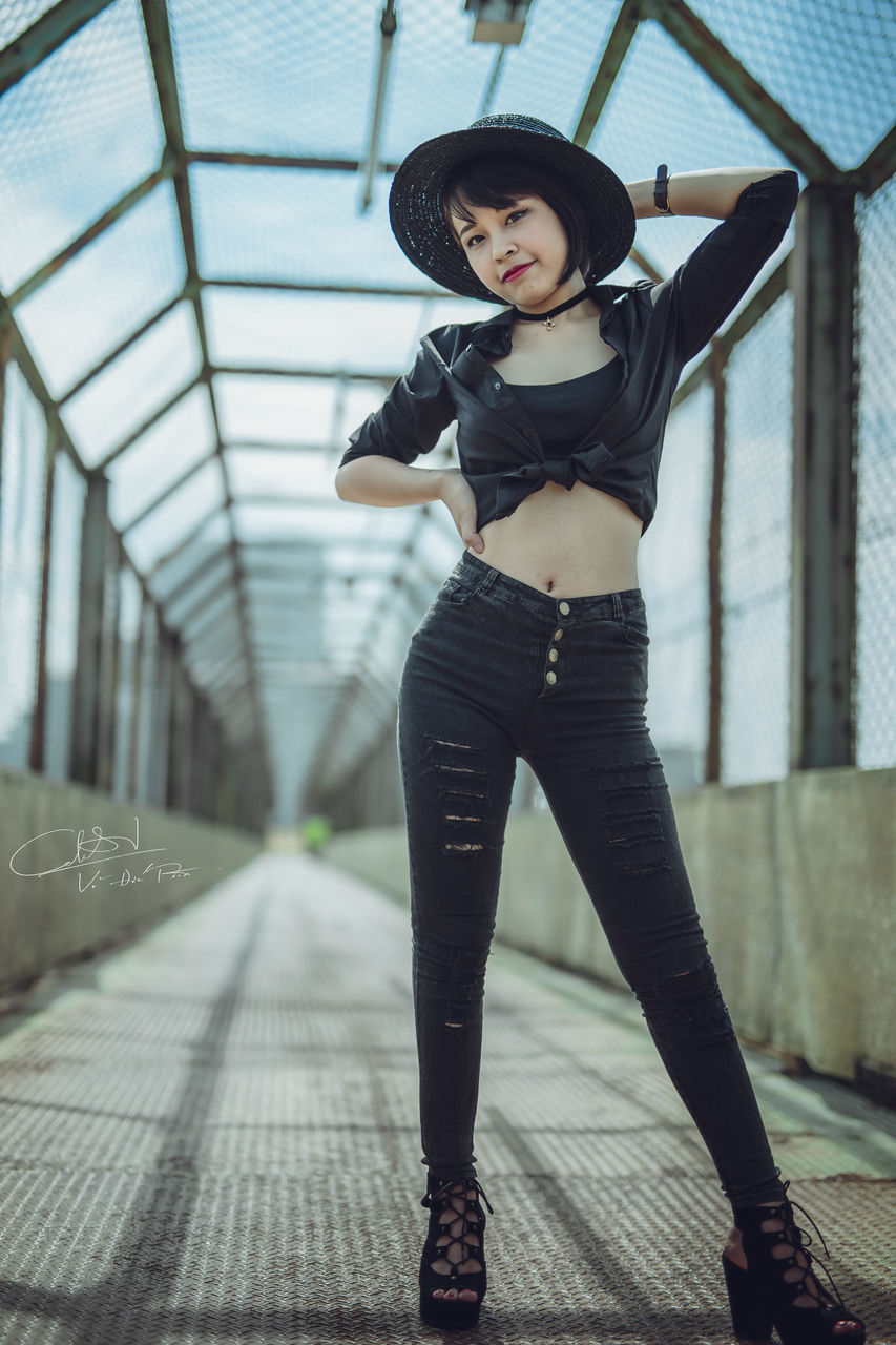 YOUNG WOMAN STANDING ON RAILING