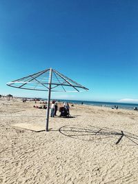 People at beach against clear blue sky