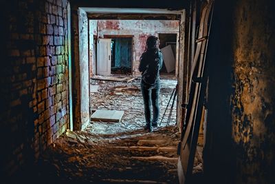 Rear view of woman standing in abandoned building