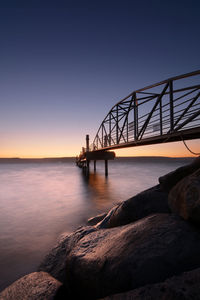 Bridge over sea against sky during sunset