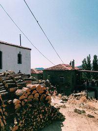 Stack of logs by buildings against clear sky