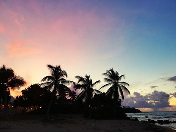 Silhouette palm trees on beach against sky at sunset