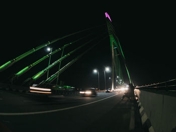 Cars on bridge against sky at night
