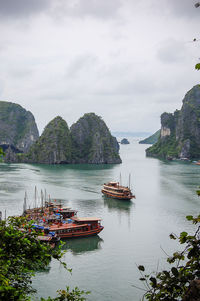 Boats and rock formations at ha long bay against sky
