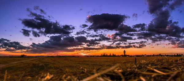 Scenic view of field against cloudy sky during sunset