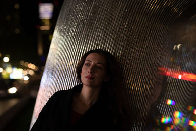 Mid adult woman leaning on pillar in city