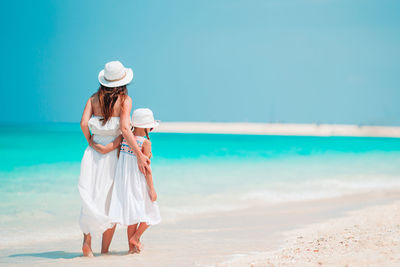 Woman with umbrella on beach against sky