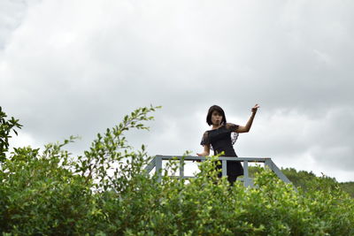 Full length of woman standing by plants against sky