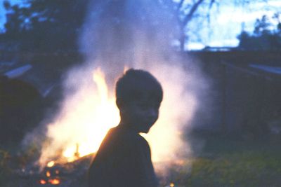 Rear view of silhouette man against illuminated light