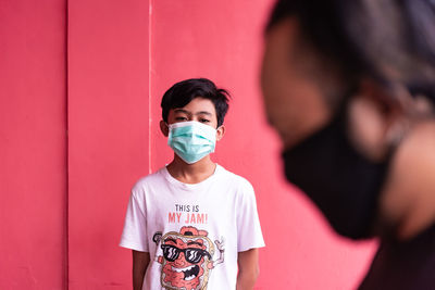 Portrait of a young man standing against wall