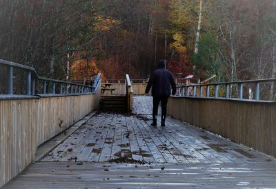 Rear view of man on footpath amidst trees during autumn