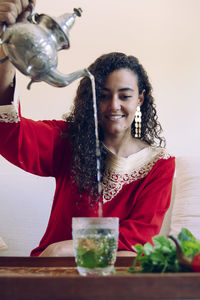 Smiling young woman pouring drink on table