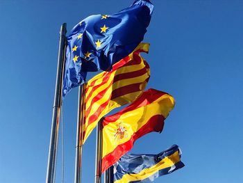 Low angle view of flags against clear blue sky