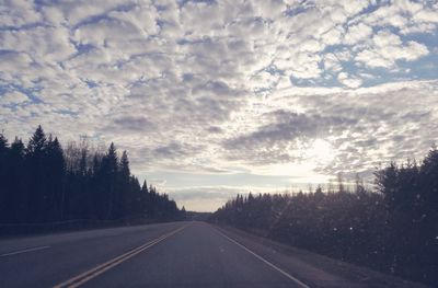 Empty road against cloudy sky