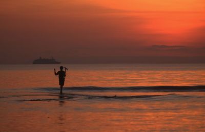 Silhouette man standing on beach during sunset