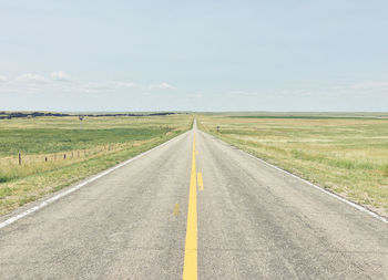 Road amidst field against sky