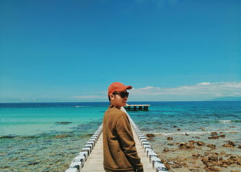 Young woman standing on pier over sea against sky