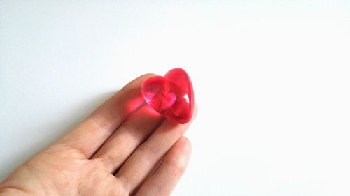 Close-up of hand holding heart shape over white background