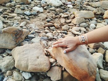 Close-up of woman hand on rocks at beach