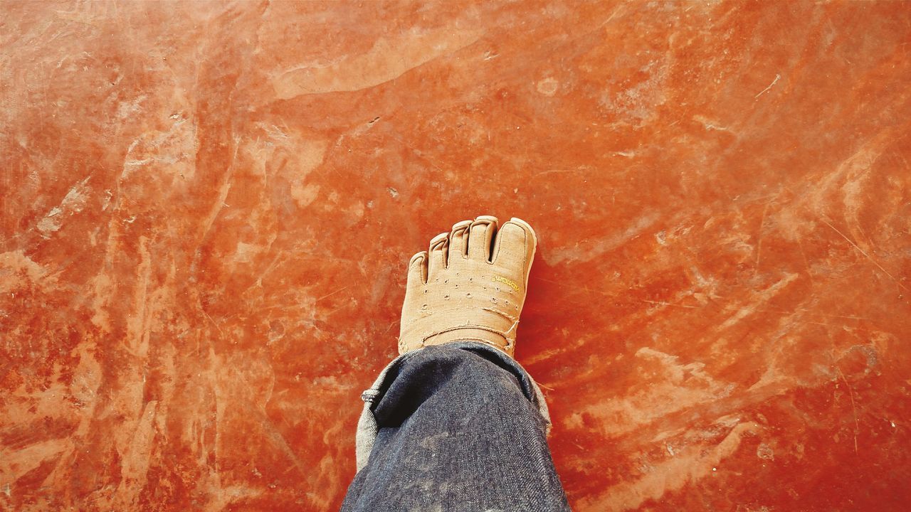 low section, personal perspective, person, shoe, red, high angle view, part of, orange color, standing, unrecognizable person, close-up, lifestyles, human foot, directly above, wall - building feature, day, footwear
