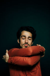 Young man with eyes closed against black background