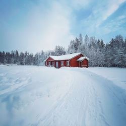 House on snow covered field against sky