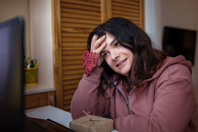 Woman holding heart shape while talking on video call