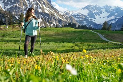 Woman hiking on field against mountains