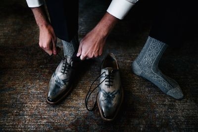 Low section of man wearing shoe on hardwood floor