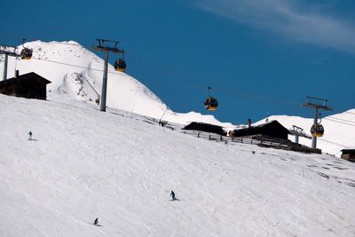 Ski lift by snow covered mountain against sky