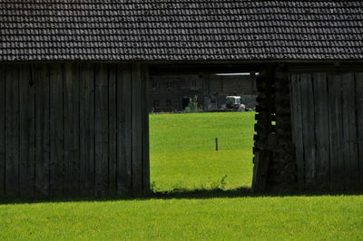 House on field seen through window of building